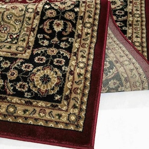 May include: Close-up of a rolled-up area rug with a traditional floral pattern. The rug features a deep burgundy border and a central design in black, beige, and burgundy. The intricate details and color palette create a classic aesthetic.