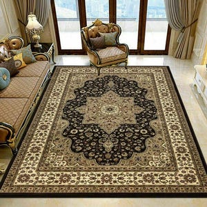 May include: A large rectangular area rug with an ornate floral design in black, beige, and brown. The rug features a central medallion and a detailed border, adding a touch of elegance to the room. The rug is placed on a tiled floor.