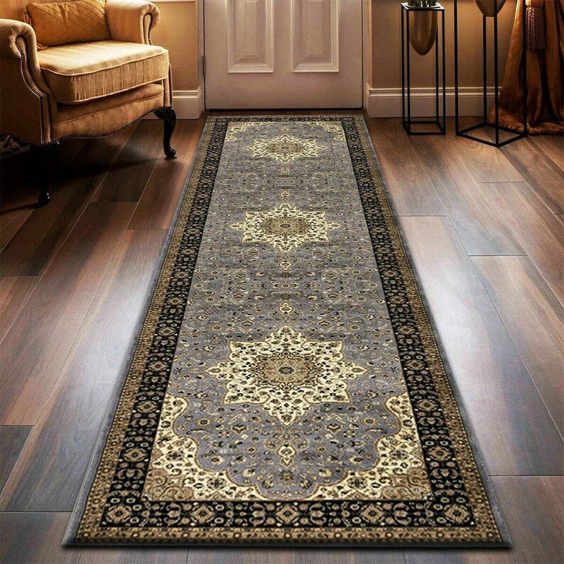 May include: A rectangular gray runner rug with an ornate floral pattern in gold and black. The rug features a central medallion design and a detailed border, suitable for a hallway or entryway.