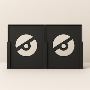 Op de afbeelding: Twee zwarte, vierkante decoratieve panelen met een cirkelvormig ontwerp. Elk paneel heeft een witte cirkel die wordt doorgesneden door een diagonale lijn, met een zeshoek in het midden. De panelen staan tegen een neutrale achtergrond.