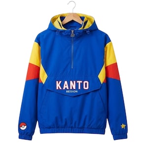 May include: Blue, yellow, and red hooded jacket with the text "KANTO REGION" across the chest. The jacket has a half-zip closure, a front pocket, and a small Pokemon logo on the left sleeve. A star is on the right sleeve.