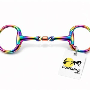 May include: A multi-coloured horse bit with a ring at each end and a central joint. The bit has a metallic finish and is attached to a white tag with the text "SUNSHINE BITS" and a logo.