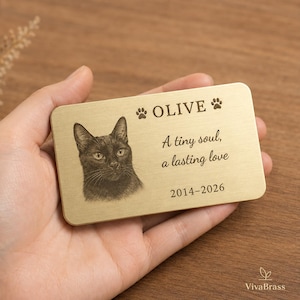May include: A rectangular brushed brass memorial card featuring an engraved portrait of a cat, the name OLIVE, two paw prints, the text A tiny soul, a lasting love, and the years 2014-2026. The metal card has rounded corners and a smooth finish.