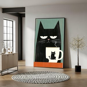 Peut inclure: Une affiche encadrée représentant un grand chat noir stylisé avec une expression renfrognée. Le chat tient une tasse avec une illustration de chat. Le fond est turquoise et orange, avec un cadre noir. L'affiche est appuyée contre un mur blanc.