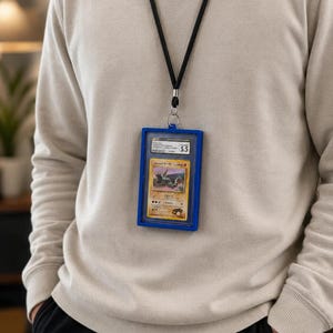 May include: A blue plastic protective case containing a graded Japanese trading card, suspended from a black lanyard. The card features a creature illustration and Japanese text, with a label at the top indicating a grade of 5.5.