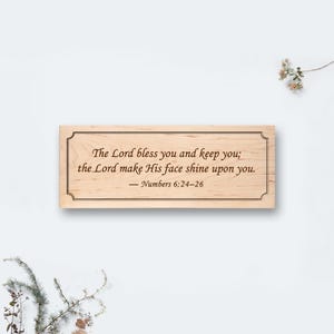 Könnte beinhalten: Rechteckige Holzplakette mit dekorativem Rahmen. Der Text "The Lord bless you and keep you; the Lord make His face shine upon you. Numbers 6:24-26" ist in klassischer Schrift graviert.