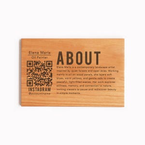 Peut inclure: Panneau en bois avec le mot « ABOUT » en grosses lettres. Le panneau comprend également le nom de l'artiste, « Elena Maris, Oil Painter », un code QR et un compte Instagram. Le panneau décrit le travail de l'artiste.