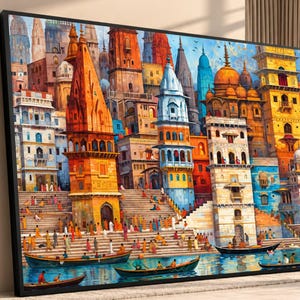 Peut inclure: Une grande impression d'art mural rectangulaire encadrée représentant un paysage urbain vibrant et coloré de Varanasi, en Inde. La scène présente de hautes tours de temple ornées dans des tons orange, jaune et bleu, avec des marches en pierre.