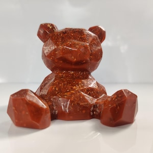 May include: A red, geometric teddy bear figurine with a textured, glittery finish.