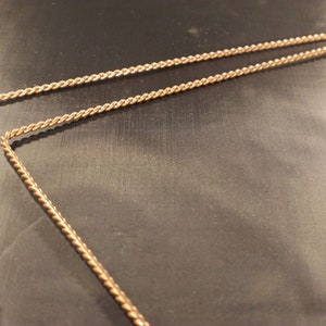 Puede incluir: Dos piezas de alambre de oro trenzado, cada una doblada en ángulo recto.