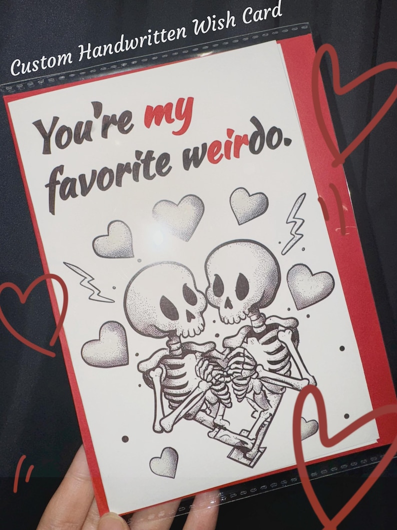 May include: Custom handwritten wish card with the text "You're my favorite weirdo." The card features a black and white illustration of two skeletons embracing, surrounded by hearts and lightning bolts, with a red border.