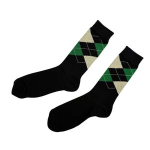 Puede incluir: Un par de calcetines negros con un diseño de rombos en verde y blanco roto. Los calcetines están hechos de un material suave y son adecuados para el uso diario. El diseño de rombos se encuentra en la parte superior de los calcetines.