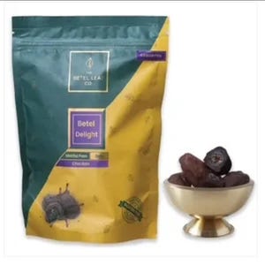 May include: A package of "Betel Delight" chocolate-flavored treats from The Betel Leaf Co. is shown next to a small gold bowl filled with dark-colored, round candies. The packaging is teal and gold.