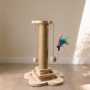 May include: A light-coloured wooden cat scratching post featuring a central sisal-wrapped column, a flower-shaped base, two hanging sisal balls suspended from the top, and a spring-mounted toy with colourful teal and magenta feathers attached.
