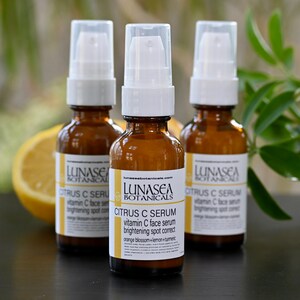 K&ouml;nnte beinhalten: Drei bernsteinfarbene Glasflaschen mit wei&szlig;en Pumpenk&ouml;pfen, gef&uuml;llt mit einem Serum mit Zitrusduft. Die Flaschen sind mit "LUNASEA BOTANICALS CITRUS C SERUM vitamin C face serum brightening spot correct orange blossom+lemon+turmeric" beschriftet.