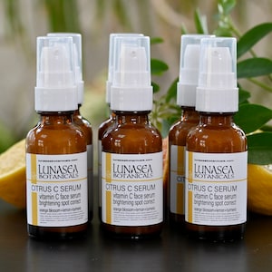 K&ouml;nnte beinhalten: F&uuml;nf bernsteinfarbene Glasflaschen mit wei&szlig;en Pumpenk&ouml;pfen, gef&uuml;llt mit einem Serum auf Citrusbasis. Die Flaschen sind mit "LUNASEA BOTANICALS CITRUS C SERUM vitamin C face serum brightening spot correct orange blossom+lemon+turmeric" beschriftet.