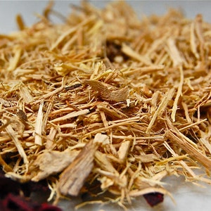 May include: Close-up of a pile of dried, light brown, shredded root bark. The bark is thin and fibrous, with a slightly rough texture.