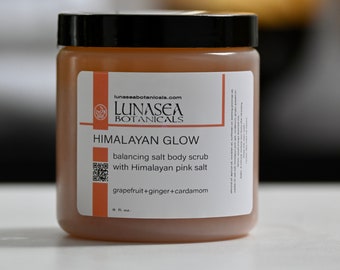 May include: A clear glass jar with a black lid containing a pink Himalayan salt body scrub. The label reads "LUNASEA BOTANICALS" and "HIMALAYAN GLOW balancing salt body scrub with Himalayan pink salt grapefruit+ginger+cardamom 8 fl. oz."