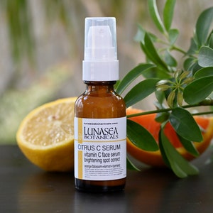 May include: A brown glass bottle with a white pump dispenser containing a citrus C serum. The bottle is labeled "LUNASEA BOTANICALS CITRUS C SERUM vitamin C face serum brightening spot correct orange blossom+lemon+turmeric".