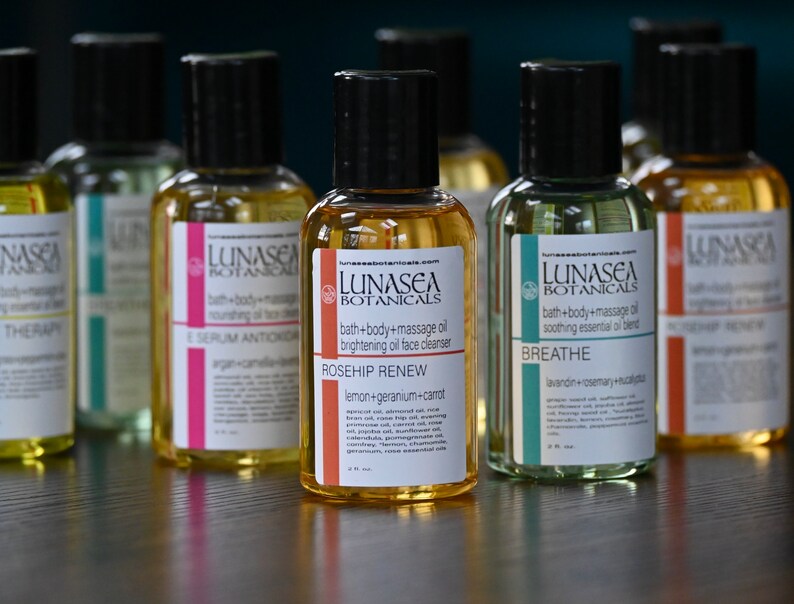 May include: Six amber glass bottles with black caps and labels. The labels are white with black text and feature the brand name "LUNASEA BOTANICALS". Each bottle has a different name and description of the product inside. The names are "THERAPY", "SERUM ANTIOXIDANT", "ROSEHIP RENEW", "BREATHE", and "WINTER RELAXER".