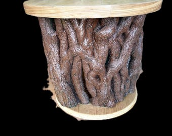 May include: A brown, tree trunk-style side table with a round, light-coloured wooden top and base. The table's body is textured to resemble tree bark, creating a rustic aesthetic. The table is approximately 50 cm in height.