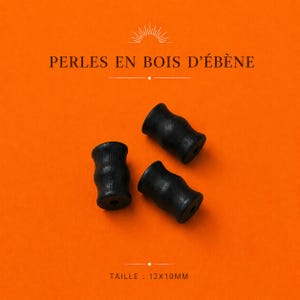 Puede incluir: Tres cuentas de madera de ébano negro con forma cilíndrica contorneada y un orificio central. El texto PERLES EN BOIS D'ÉBÈNE y TAILLE : 12X10MM es visible sobre el fondo naranja. Estas cuentas presentan un acabado oscuro y liso.