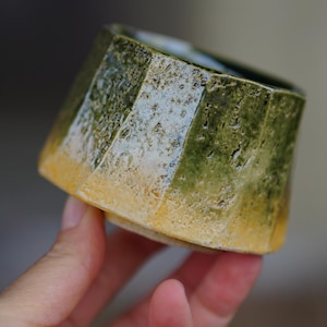 Könnte beinhalten: Ein Set aus drei Keramikbechern mit gesprenkelter, matter Oberfläche. Die Becher sind in den Farbtönen Creme, Hellgrau und Dunkelgrau gehalten. Jeder Becher hat ein schlichtes, minimalistisches Design, ideal für Kaffee oder Tee.