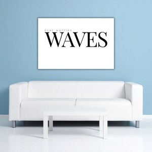 Könnte beinhalten: Ein weißes, rechteckiges Wandbild mit den Worten "over worries" über "WAVES" in schwarzer Schrift. Das Bild hängt über einem weißen Sofa und einem passenden Couchtisch vor einer hellblauen Wand.
