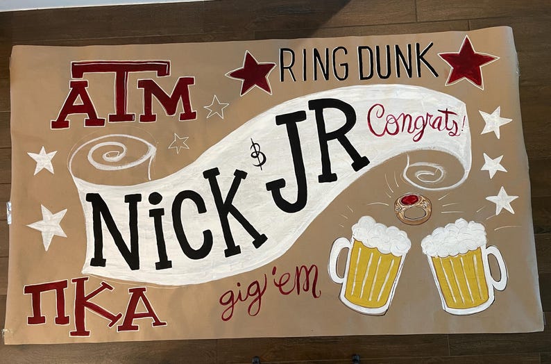 Op de afbeelding: Een bruine banner met kastanjebruine en zwarte letters. De banner zegt "ATM", "Nick Jr", "Ring Dunk", "Congrats!" en "gig'em". Er zijn ster- en bierkruikillustraties.