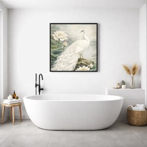 May include: A framed art print depicting a white peacock on a rock, with lotus flowers. The artwork has a soft, watercolour style and a black frame. The image is displayed above a white, oval bathtub in a modern bathroom setting.