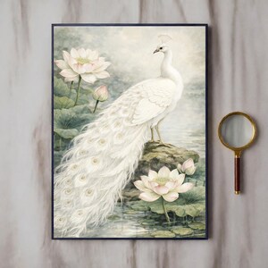 May include: A framed watercolour painting depicting a white peacock with a long tail, standing on a rock. The artwork uses soft pastel colours, with lotus flowers and lily pads in the foreground. The background shows a serene, watery landscape.