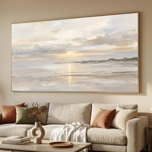 May include: A large rectangular landscape painting featuring a serene coastal scene at sunset. The artwork displays soft, blended brushstrokes in shades of cream, beige, light blue, and white, depicting a calm shoreline with a glowing sun.