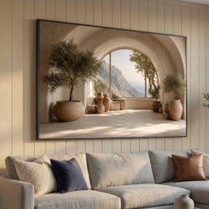 May include: A rectangular wall art print in a black frame depicting a Mediterranean-style stone archway overlooking a mountain landscape. The scene features potted olive trees and terracotta vessels on a stone floor with soft sunlight.