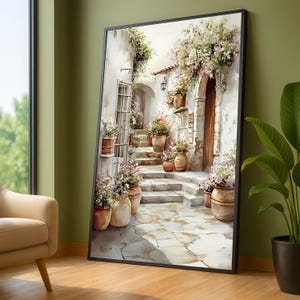 May include: A framed watercolour painting shows a sunlit Italian courtyard with stone steps, doorways, and potted flowers. The artwork has a black frame and leans against a green wall, with a glimpse of a window and a chair in the background.
