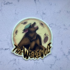 May include: A sticker featuring a brown werewolf howling at a yellow moon with craters. The werewolf wears a green hat. The text "THE WEREWOLF" is in black, stylized lettering.
