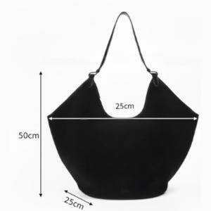 Peut inclure: Un sac fourre-tout noir avec une seule bandouli&egrave;re. Le sac mesure 50 cm de haut, 25 cm de large et 25 cm de profondeur. La poign&eacute;e du sac est une fine sangle sombre. Le sac est de forme large et ouvert.