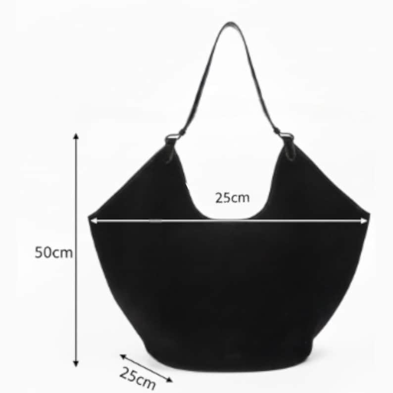 Peut inclure: Un sac fourre-tout noir avec une seule bandouli&egrave;re. Le sac mesure 50 cm de haut, 25 cm de large et 25 cm de profondeur. La poign&eacute;e du sac est une fine sangle sombre. Le sac est de forme large et ouvert.