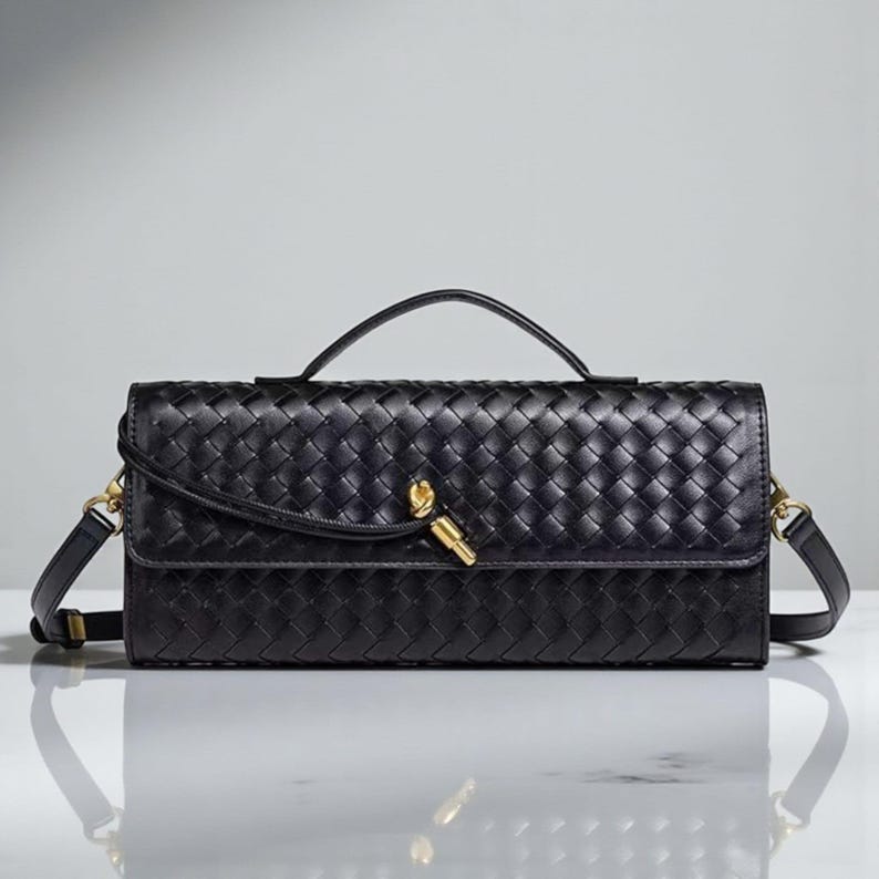 May include: A black woven leather handbag with a top handle and a detachable shoulder strap. The rectangular bag features a gold-toned clasp and hardware. The bag's design includes a woven pattern, adding texture to the accessory.