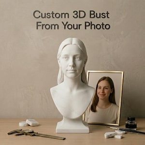 Può includere: Un busto in marmo bianco di una donna con i capelli lunghi, accanto a una foto incorniciata di una donna. Il testo "Custom 3D Bust From Your Photo" è sopra il busto. Un calibro, un flacone di inchiostro e un pennello sono sulla superficie di legno.