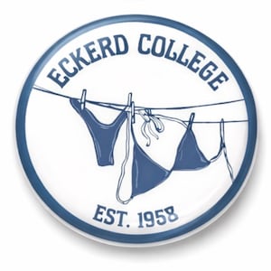 Puede incluir: Un botón redondo blanco con borde azul que muestra el texto "ECKERD COLLEGE" en una fuente curva. En el centro, una cuerda de tender con un bikini. El texto "EST. 1958" está en la parte inferior. El diseño es azul.