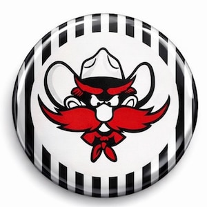 May include: A round button featuring a cartoon cowboy with a red mustache and a white hat. The cowboy is set against a white background with a black and white striped border. The button has a glossy finish.