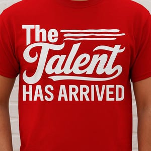 May include: A red t-shirt with the white text "The Talent HAS ARRIVED". The text is in a bold, stylized font. The shirt is a solid red color.