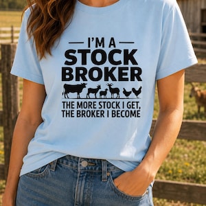 Puede incluir: Una camiseta de manga corta azul claro con texto negro que dice I'M A STOCK BROKER, seguido de siluetas de una vaca, una cabra, una oveja y dos pollos, y el texto THE MORE STOCK I GET, THE BROKER I BECOME impreso en la parte frontal.