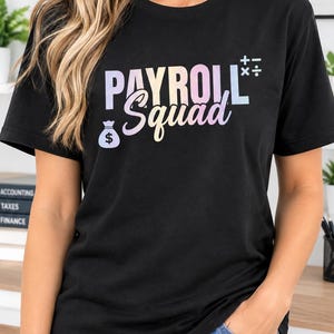 Peut inclure: Un t-shirt noir à manches courtes avec le texte "PAYROLL Squad" dans une police à dégradé pastel. Le motif comprend une petite icône de sac d'argent avec un signe dollar et des symboles mathématiques d'addition, soustraction, multiplication et division.