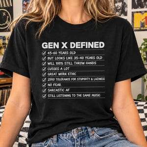 May include: A black short-sleeved t-shirt featuring white text that reads GEN X DEFINED followed by a checklist of traits including 45-60 years old, looks like 35-40 years old, will 100% still throw hands, cusses a lot, and is sarcastic AF.