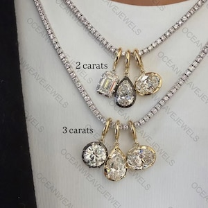 Puede incluir: Collares con colgantes de diamantes de diferentes tallas y pesos en quilates. Los collares presentan diamantes de talla redonda, pera y esmeralda engastados en oro y platino. La imagen muestra dos collares, uno con colgantes de 2 quilates y otro de 3 quilates.