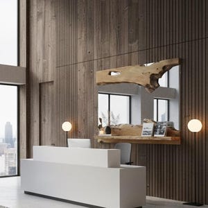 Può includere: Reception di ufficio moderna con scrivania bianca, grande specchio con cornice in legno e sculture astratte. La stanza presenta finestre a tutta altezza e vista sul paesaggio urbano.