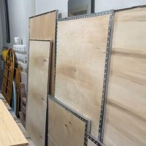 Peut inclure: Plusieurs grands panneaux rectangulaires en bois clair sont dispos&eacute;s verticalement. Chaque panneau pr&eacute;sente une surface lisse au grain naturel et est encadr&eacute; par des bandes m&eacute;talliques argent&eacute;es avec un motif r&eacute;p&eacute;titif de petits trous.