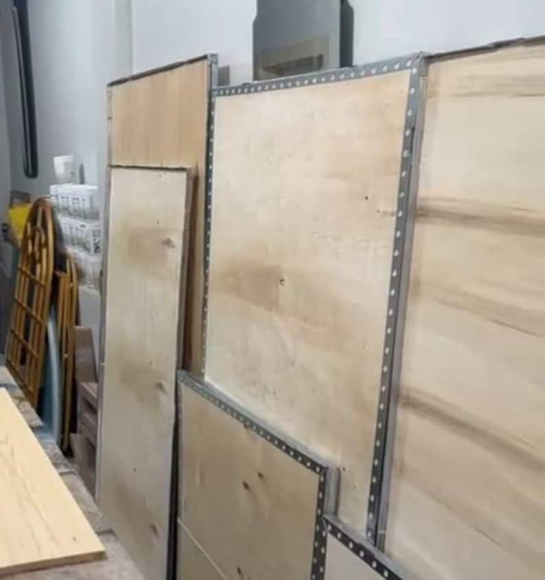 Peut inclure: Plusieurs grands panneaux rectangulaires en bois clair sont dispos&eacute;s verticalement. Chaque panneau pr&eacute;sente une surface lisse au grain naturel et est encadr&eacute; par des bandes m&eacute;talliques argent&eacute;es avec un motif r&eacute;p&eacute;titif de petits trous.