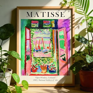 Może przedstawiać: Oprawiony wydruk "Otwarte okno, Collioure" Matisse'a z 1905 roku. Grafika przedstawia kolorowy widok z okna z łodziami. Rama jest w jasnym kolorze drewna, a u góry znajduje się napis "MATISSE".